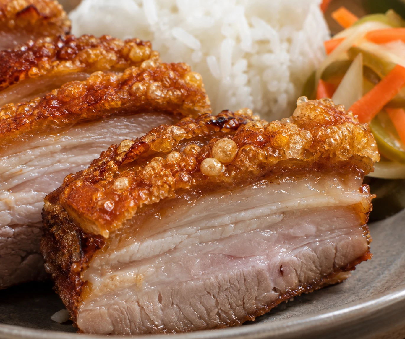 Deep-golden blistered crackling caps tender layers of sliced pork belly over jasmine rice.