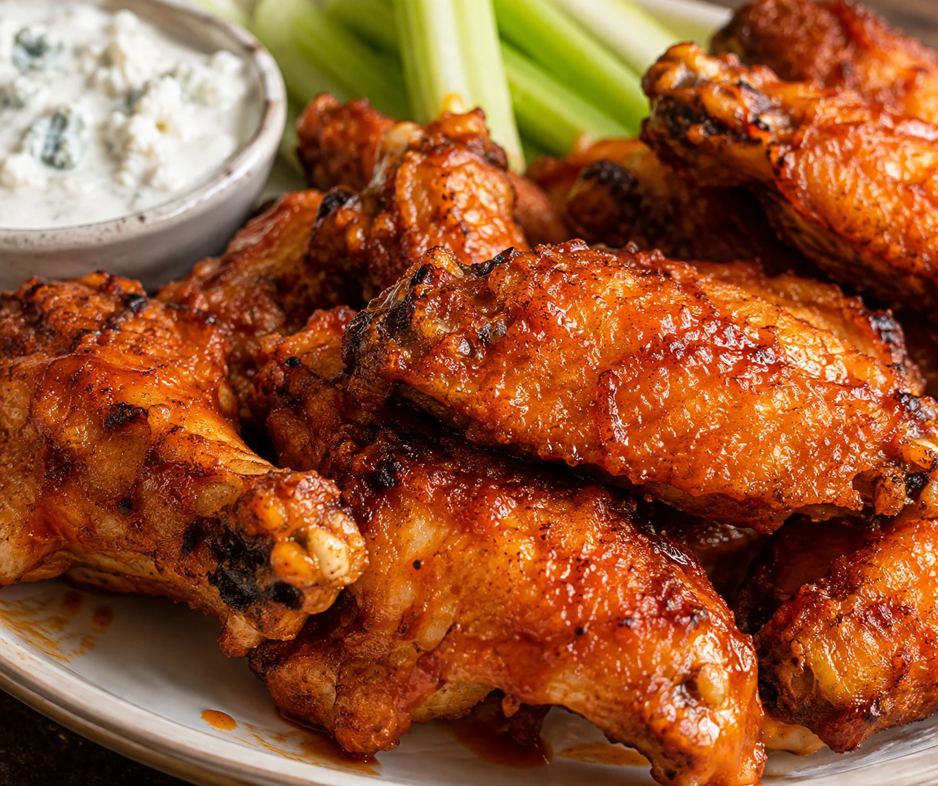 A close view shows crisp golden wing skin under glossy cayenne-butter sauce.