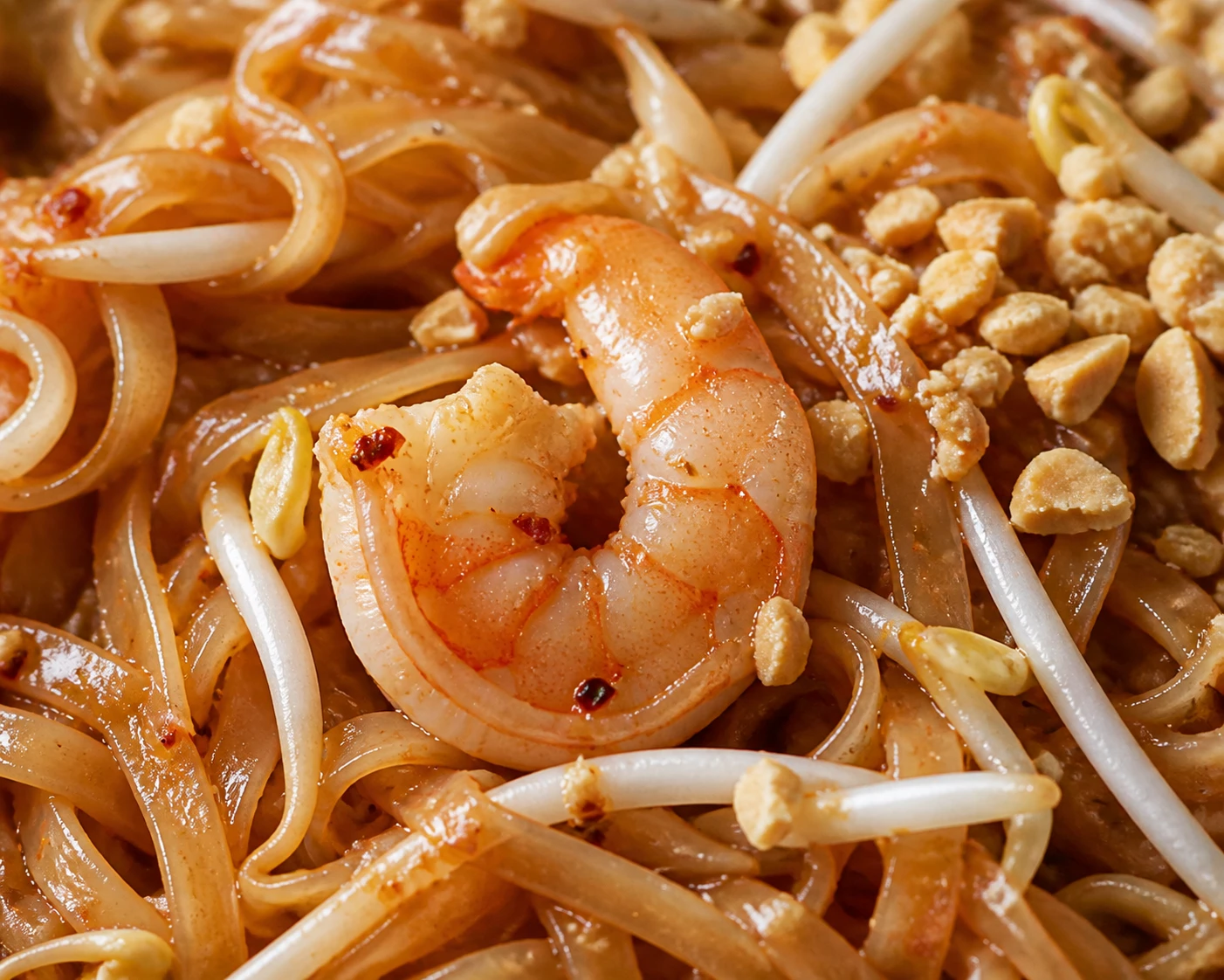 Glossy rice noodles with tender protein, crisp bean sprouts, crushed peanuts, and chili flakes.