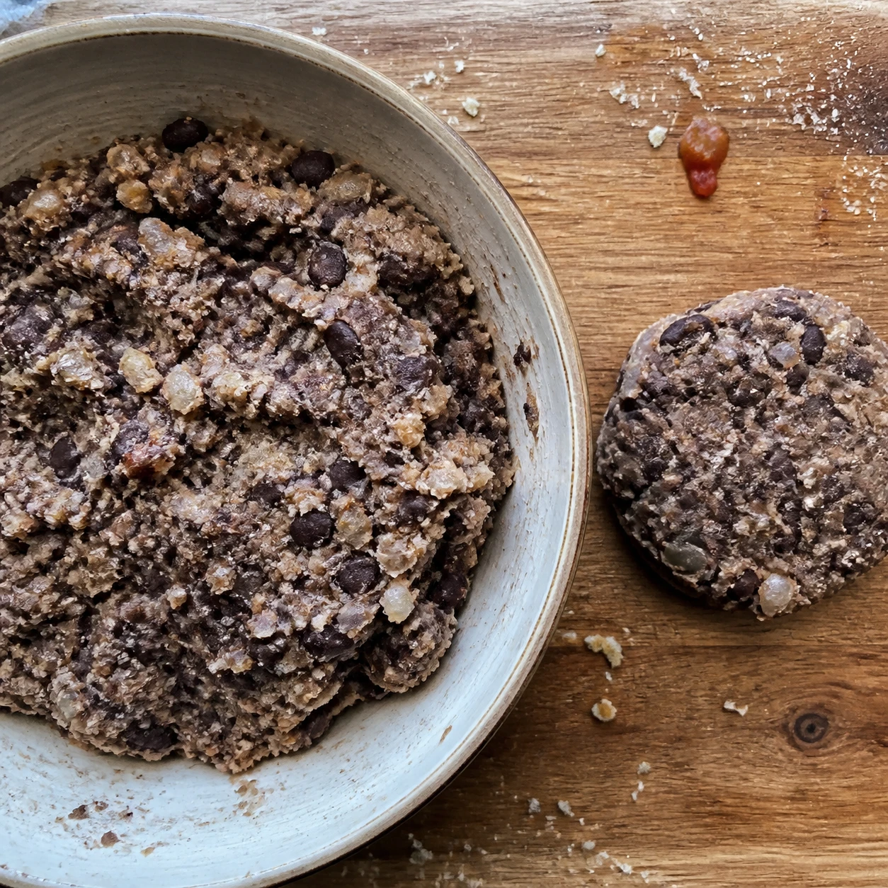 Black bean burger batter with diced onion, chipotle-adobo, spices, and panko is being formed into patties.