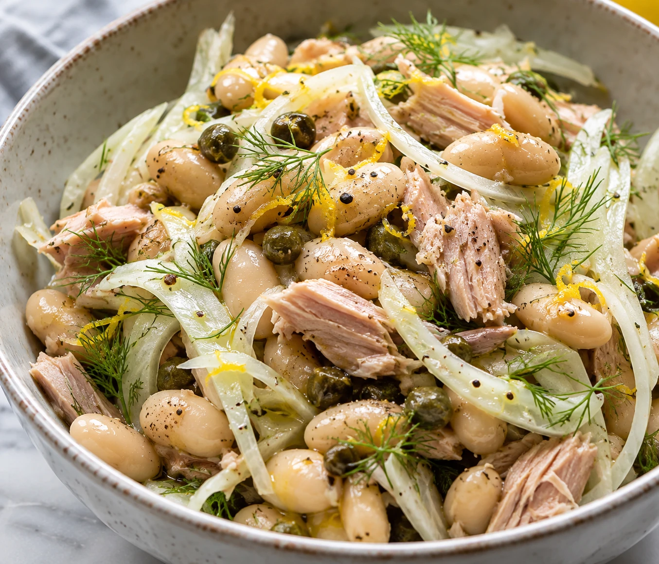 Glossy beans and intact tuna flakes sit beneath delicate fennel slices and fresh fronds.